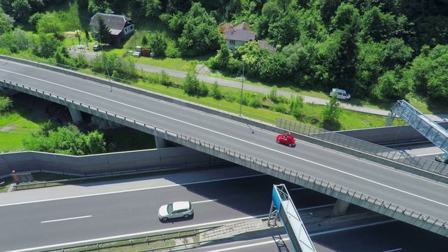 Red vintage car driving on a country road overpassing highway