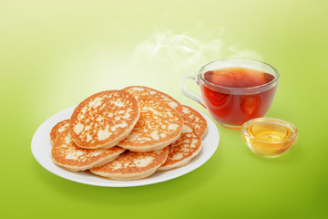 Stack of fresh baked pancakes with butter, honey and hot tea.