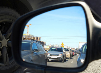 Отражение автомобильной пробки во внешнем зеркале заднего вида автомобиля