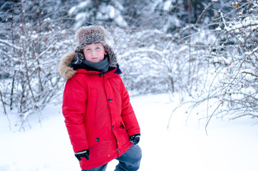 Boy in a red parka in the winter forest