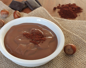 Schokoladen-Nuss Pudding mit Zutaten im Hintergrund in einer weißen Schüssel 