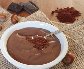 Schokoladen-Nuss Pudding mit Zutaten im Hintergrund in einer weißen Schüssel 