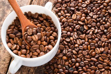 coffee beans on a table in a white cup with a wooden spoon