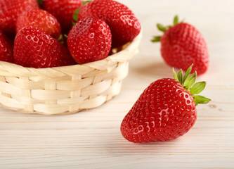 strawberries in small basket on a wooden background