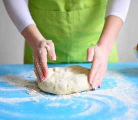 Woman's hands knead dough on a table