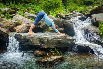 Woman doing yoga oudoors at tropical waterfall