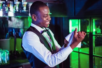 Smiling bartender cleaning a glass