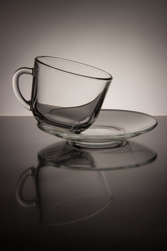 Glass empty mug of tea and saucer on a black and white backgroun