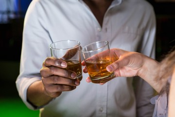 Couple toasting their whisky glasses in bar