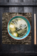 Miso soup in blue bowl on dark rustic background, top view