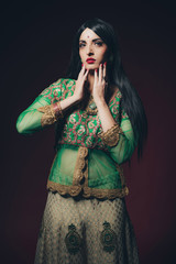 Traditional vintage Bollywood fashion girl against dark red back