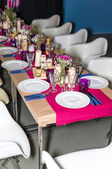 Decorated table ready for dinner. Beautifully decorated table set with flowers, candles, plates and serviettes for wedding or another event in the restaurant.