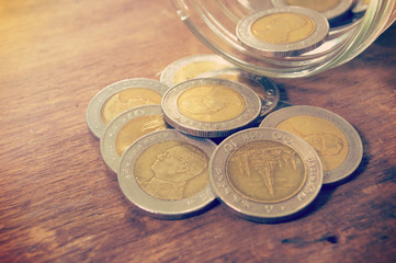 coins in bottle on old wooden background