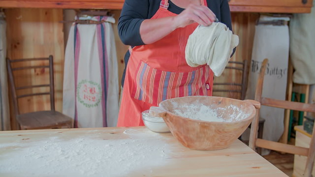 Lady kneading the dough in the wooden bool 