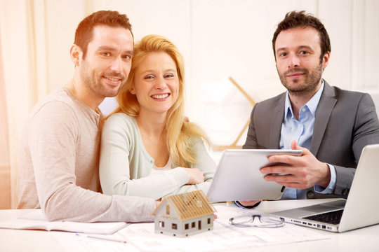 Real estate agent present project on tablet to a young couple