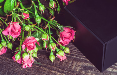 small bouquet of roses and gift on a wooden background