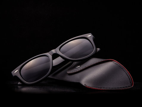 Black Sunglasses With Case On Black Background.