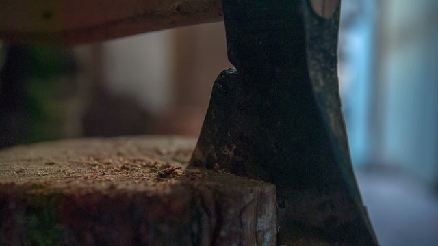 Man slamming the axe in to the log standing in the middle of a cabin close up footage in slow motion.
