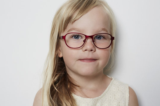 Cute little girl in glasses looking at camera