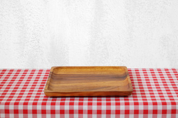 Empty wooden tray on table with red tablecloth