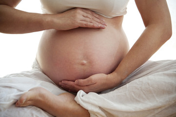 Fototapeta na wymiar Closeup of pregnant woman meditating at white background