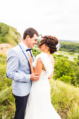 Bride and groom at wedding Day walking Outdoors on spring nature. Happy Newlywed  embracing in green park. 