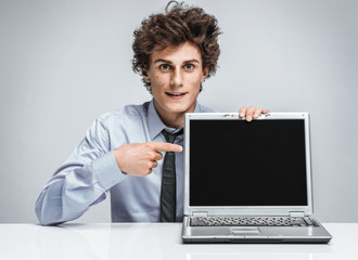 Young salesman showing at screen laptop / modern businessman at the workplace working with computer