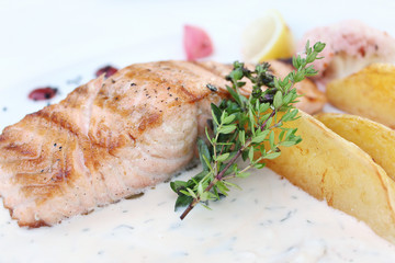 Baked salmon with potato slices, and thyme sauce. 