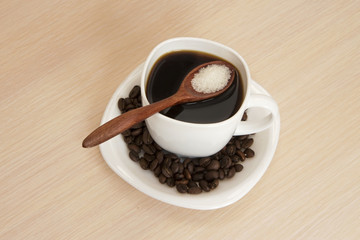 Cup of coffee on a table with a wooden spoon and sugar