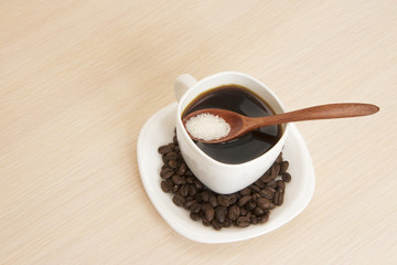 Cup of coffee on a table with a wooden spoon and sugar