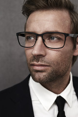 Man in suit and smart spectacles, looking away