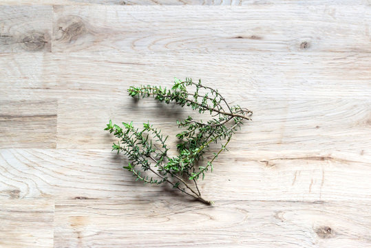 fresh branch of thyme on an oak tree cutting board seen from the top