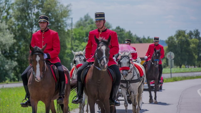 Men in red uniforms on horses and a carriage