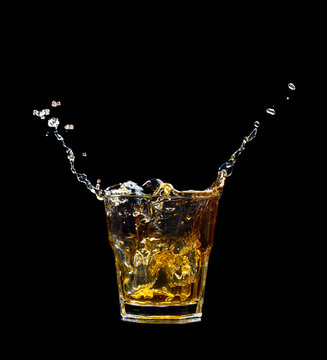 Whiskey splash in glass isolated on black background.