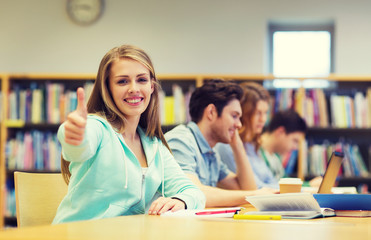 happy student girl showing thumbs up in library