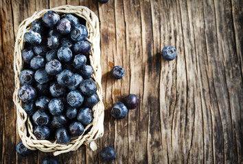 Fresh blueberries in basket om wooden background