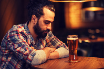 unhappy lonely man drinking beer at bar or pub