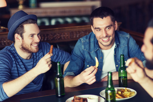 happy male friends drinking beer at bar or pub