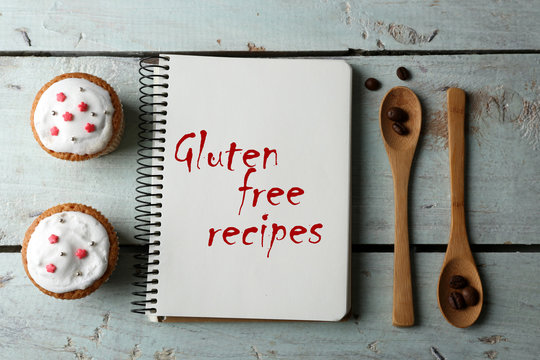 Open recipe book and text Gluten free recipes on wooden background