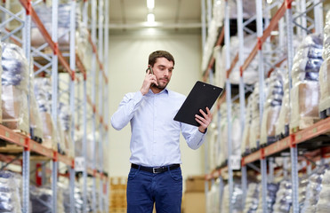 man with clipboard and smartphone at warehouse