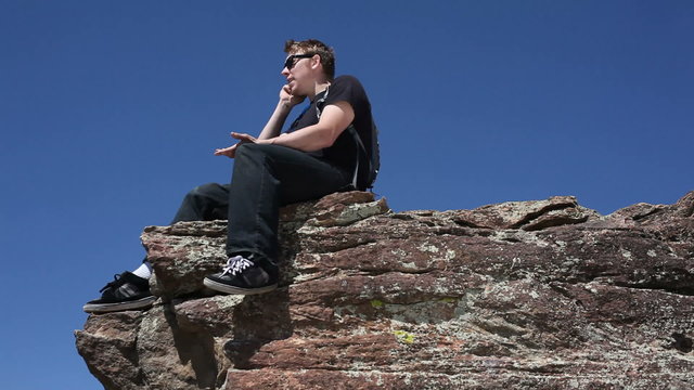 Young man on cliff with cell phone