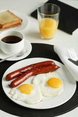 Breakfast. Fried eggs with sausages served on white table