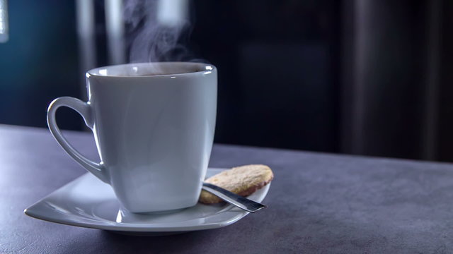 Something falls into a coffee and a few coffee drops fall out of a cup