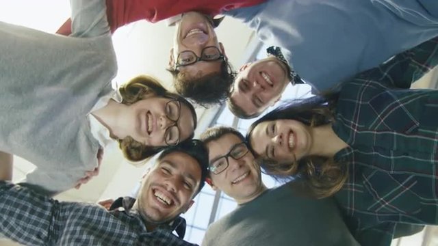 Multi-ethnic group of happy young students are standing in a circle and looking down at the camera. Shot on RED Cinema Camera.