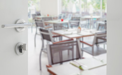 opened white door to wooden table and chair in a restaurant