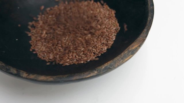 Linseeds flax pouring into rustic bowl close-up Isolated video