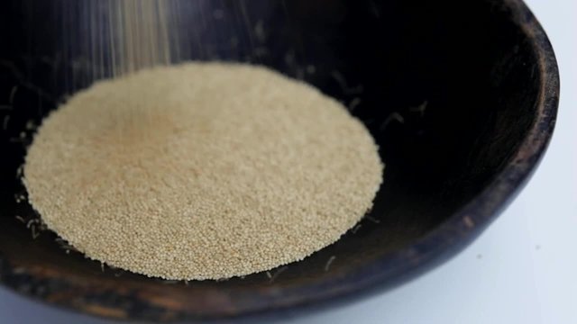 Amaranth seeds pouring into rustic bowl close-up Isolated video 