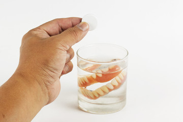 Hand holding cleaning tablets to a glass of False Teet