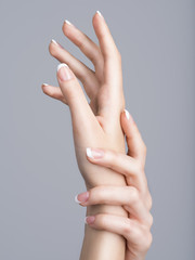 Schöne weibliche Hände mit französischer Maniküre auf den Nägeln
