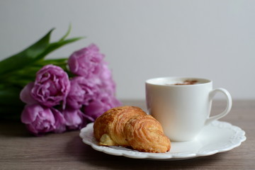 cup of cuppuccino and yummy croissant with flowers